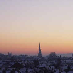 A snowy winter sunset photo looking across the city rooftops towards the Malvern Hills.