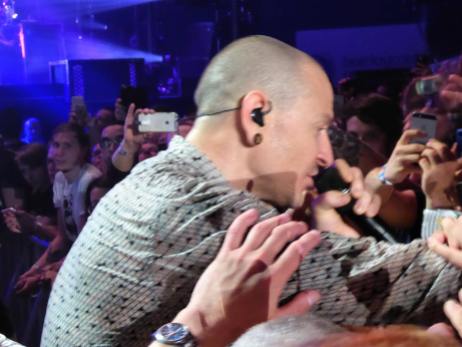 Close up side profile of Chester at floor level singing to us fans and holding their hands.