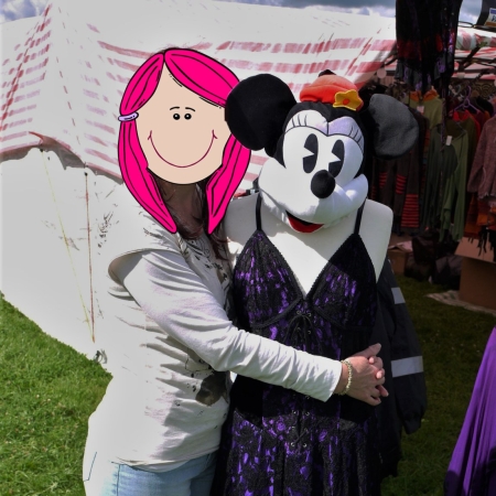 I'm standing with my arms round a mannequin that is wearing a Minnie Mouse face mask and a long purple dress. My identity is hidden behind a cartoon face with pink hair.