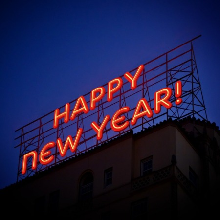 Large red neon sign above a building, against a twilight sky, saying 'Happy New Year'.