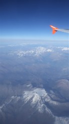 View from plane window overlooking The Alps. The plane's wingtip can be seen on the top right corner.